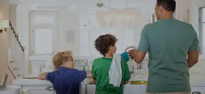 Children and father washing dishes at kitchen sink
